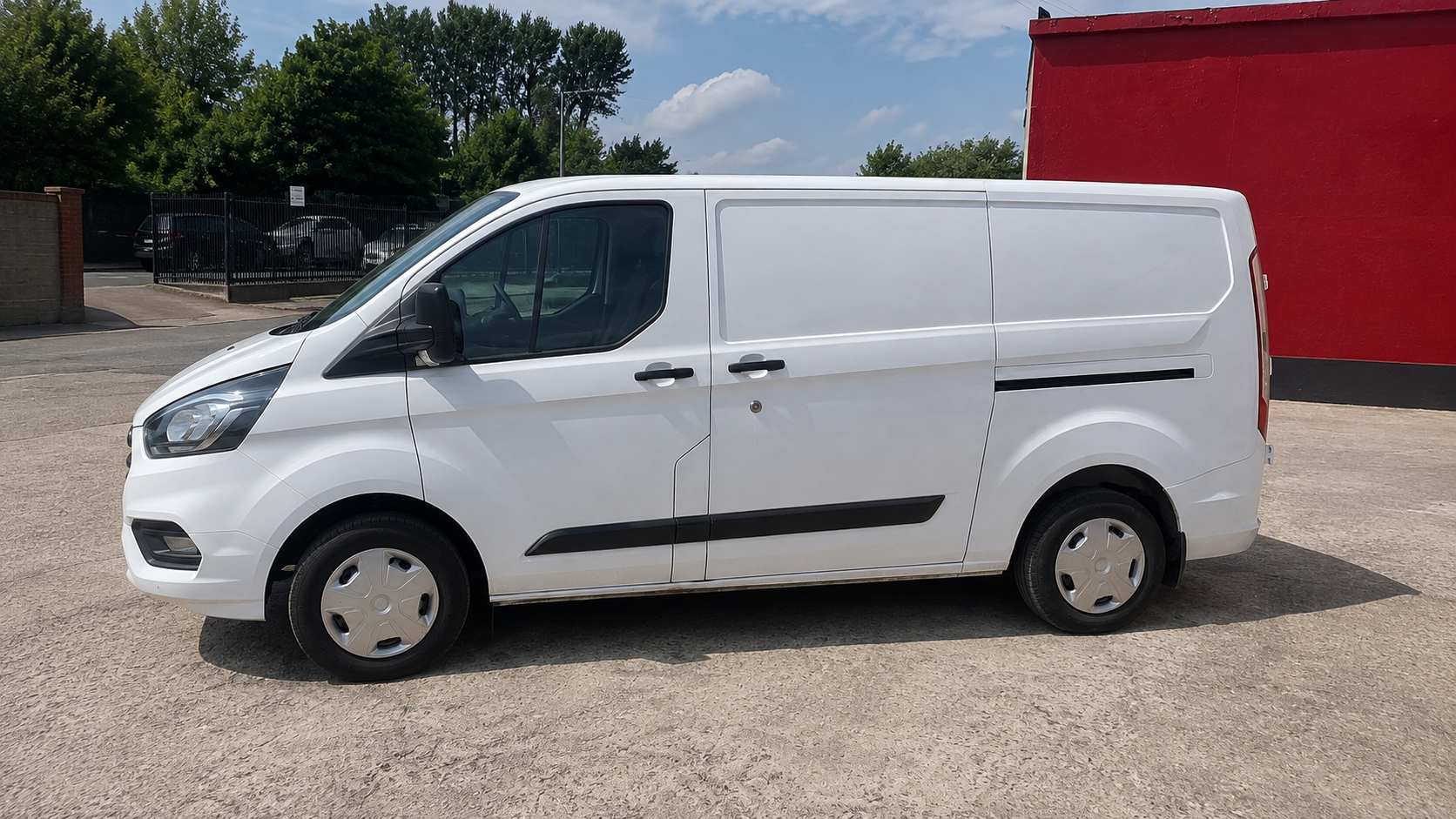 Side view of the finished white Ford Transit Custom outside the Portadown workshop, showing an even paint finish along the panels