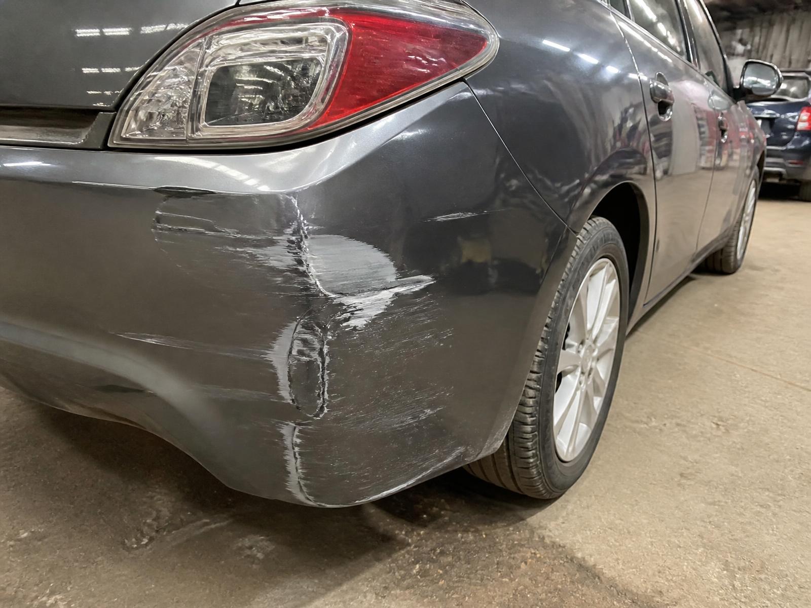 Dented and scraped rear quarter panel on a dark car — repairable body damage